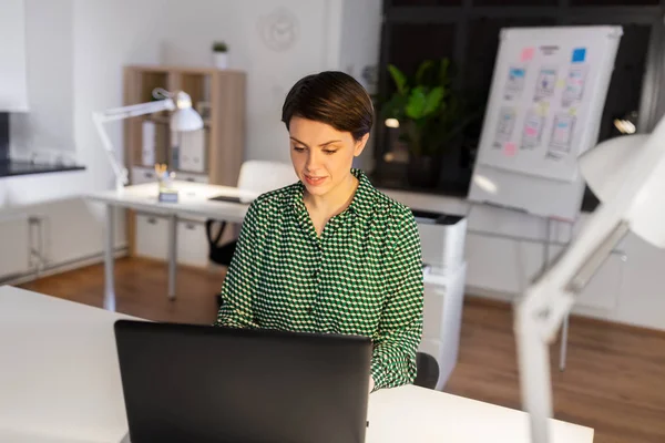 Business woman working on laptop at night office — стоковое фото