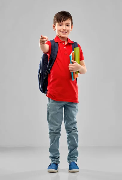 Estudiante chico con libros y bolsa apuntando a usted — Foto de Stock