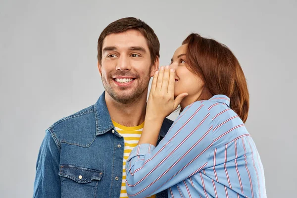 Feliz pareja susurrando sobre gris fondo — Foto de Stock