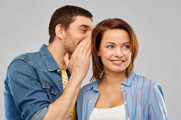 Glückliches Paar flüstert über grauen Hintergrund — Stockfoto