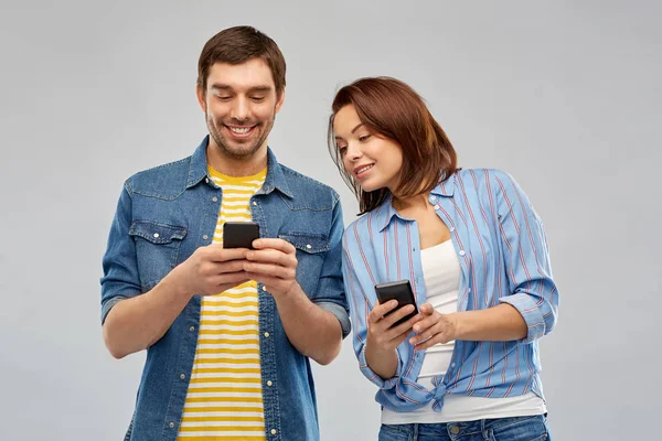 Szczęśliwa para za pomocą smartfonów na szaro — Zdjęcie stockowe
