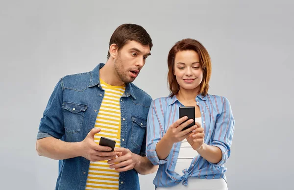 Pareja usando teléfonos inteligentes sobre fondo gris — Foto de Stock