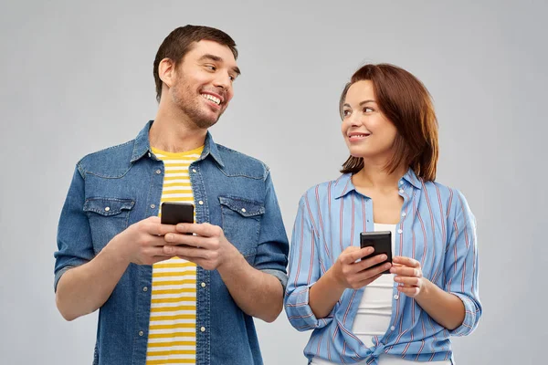 Casal feliz com smartphones falando — Fotografia de Stock