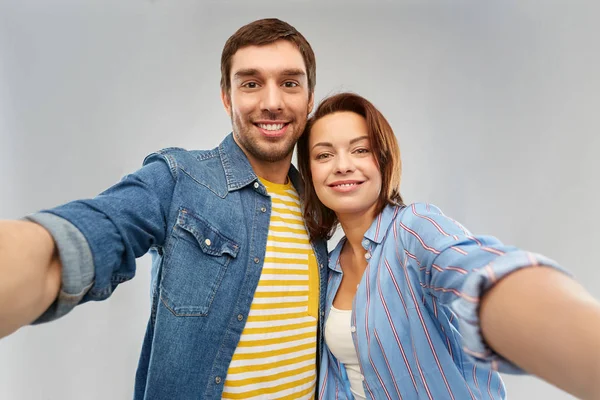 Szczęśliwa para biorąc selfie na szarym tle — Zdjęcie stockowe