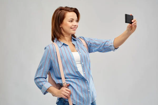 Женщина с рюкзаком делает селфи на смартфоне — стоковое фото