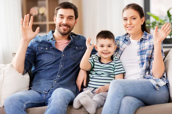 Portrait de famille heureuse agitant les mains à la maison — Photo