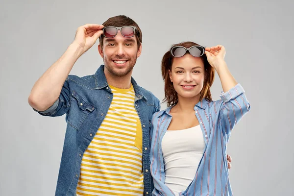 Couple heureux dans des lunettes de soleil sur fond gris Image En Vente