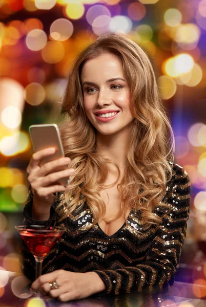 Woman with cocktail and smartphone at bar — Stock Photo, Image