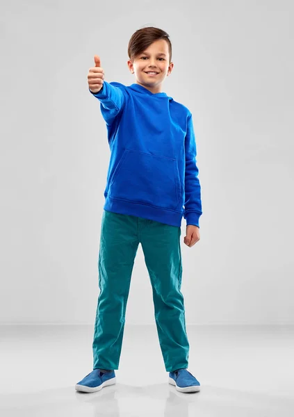 Sonriente chico en azul sudadera con capucha mostrando pulgares hacia arriba — Foto de Stock