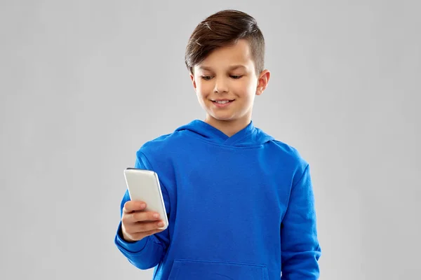 Menino sorridente com capuz azul usando smartphone — Fotografia de Stock