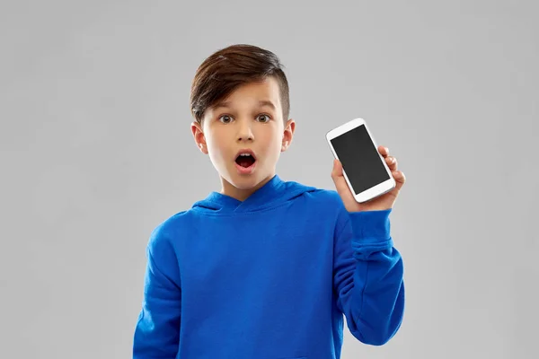 Шокований хлопчик у блакитному светрі, що показує смартфон — стокове фото