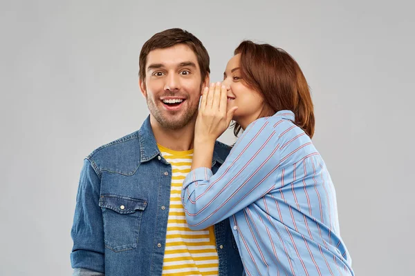 Feliz pareja susurrando sobre gris fondo — Foto de Stock