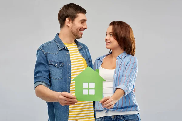 Улыбающаяся пара держит зеленый бумажный дом — стоковое фото