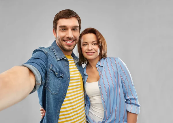 Happy couple taking selfie over grey background — Stock Photo, Image