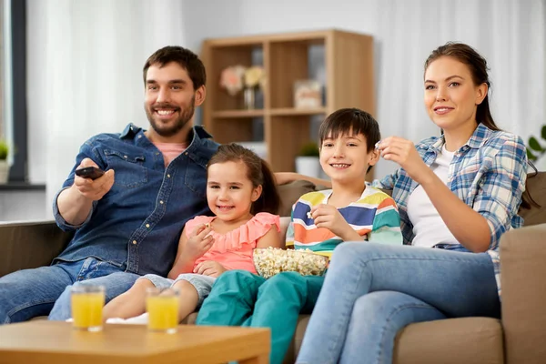 Šťastná rodina s popcornem dívat se na televizi doma — Stock fotografie
