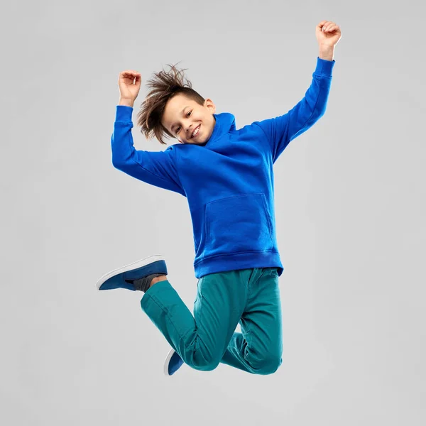 Portrait of smiling boy in blue hoodie jumping Royalty Free Stock Images