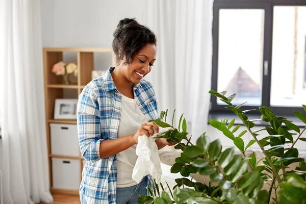 快乐的女人在家里清洁室内植物 — 图库照片
