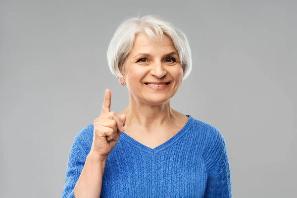 Sonriente mujer mayor señalando el dedo hacia arriba — Foto de Stock