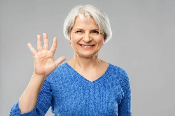 Tersenyum wanita senior menunjukkan telapak tangan atau lima jari — Stok Foto
