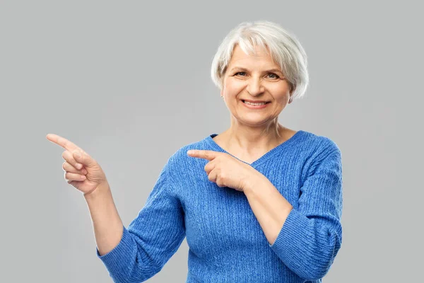 Usmívající se starší žena ukazujícími prstem na něco — Stock fotografie