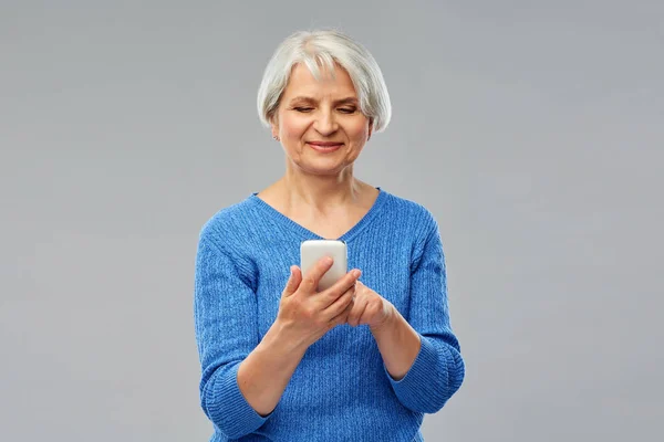 Lachende senior vrouw gebruikend smartphone — Stockfoto