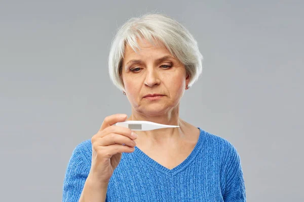Больная пожилая женщина с термометром — стоковое фото