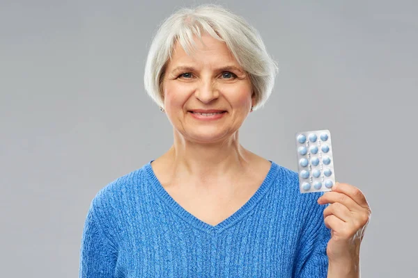 Smiling senior woman with pack of pills — Stock Photo, Image