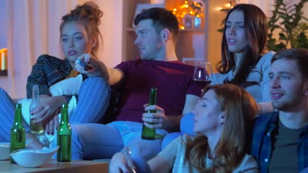 Друзі з напоями і закусками дивитися телевізор вдома — стокове відео