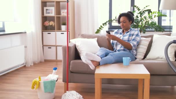 Žena s chytrým telefonem odpočinku po domácím čištění — Stock video