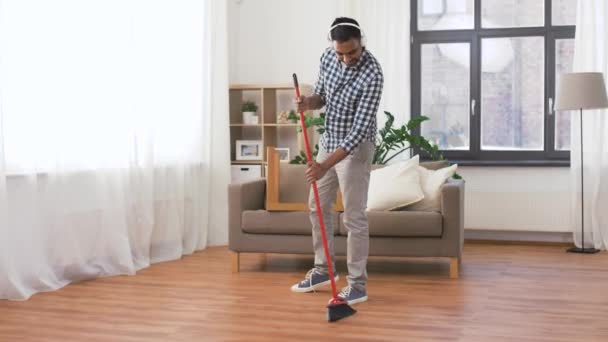 Uomo in cuffia con scopa pulizia a casa — Video Stock