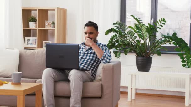 Hombre con ordenador portátil después de la limpieza del hogar — Vídeos de Stock