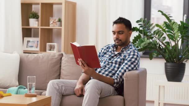 Homem lendo livro e descansando após a limpeza em casa — Vídeo de Stock