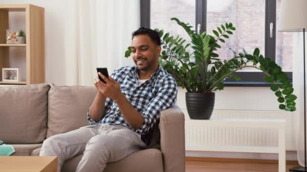 Uomo indiano utilizzando smartphone dopo la pulizia della casa — Video Stock