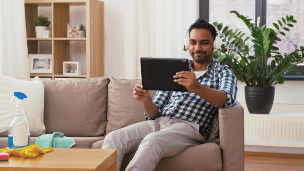 Hombre en auriculares con PC tableta después de la limpieza — Vídeo de stock