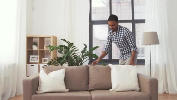 Indian man arranging sofa cushions at home — Stock Video