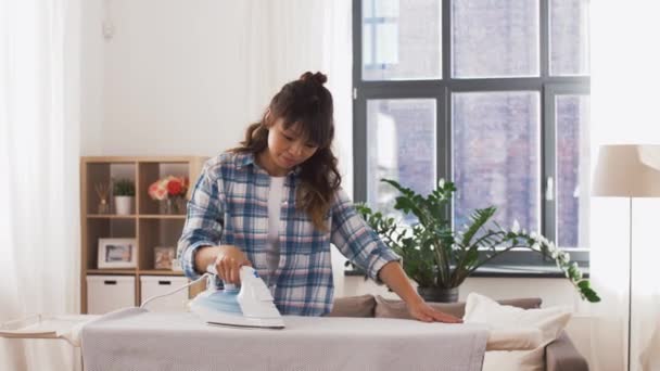 Mujer asiática planchando ropa de cama en casa — Vídeos de Stock