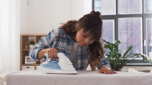 Mujer asiática planchando ropa de cama en casa — Vídeos de Stock