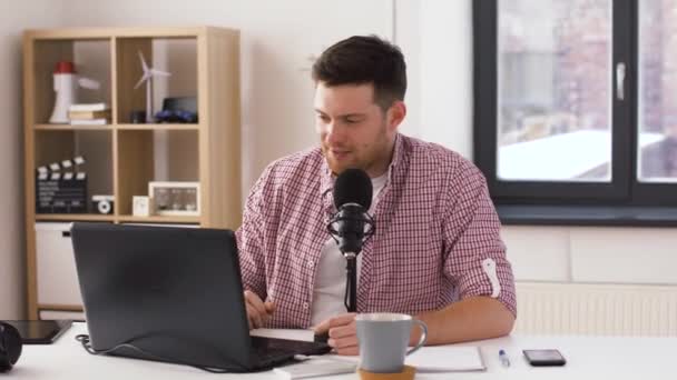 Счастливый молодой человек с ноутбуком и микрофоном дома — стоковое видео