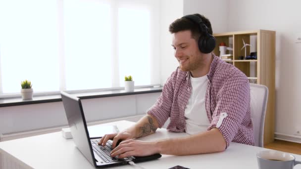 Homem feliz em fones de ouvido com laptop no escritório — Vídeo de Stock