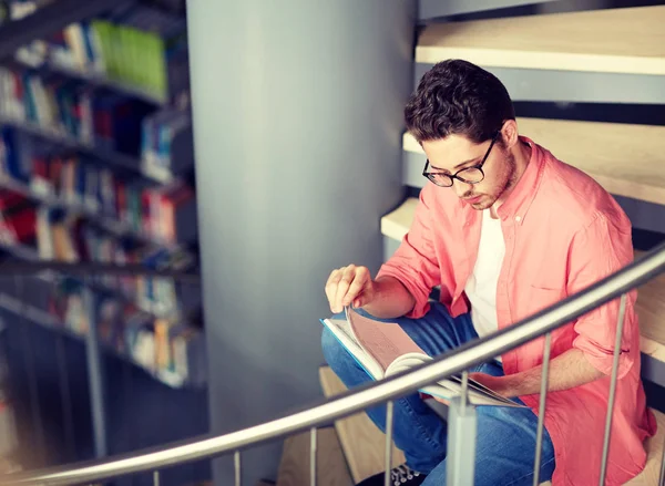 Student jongen of jonge man lezing boek bij de bibliotheek — Stockfoto