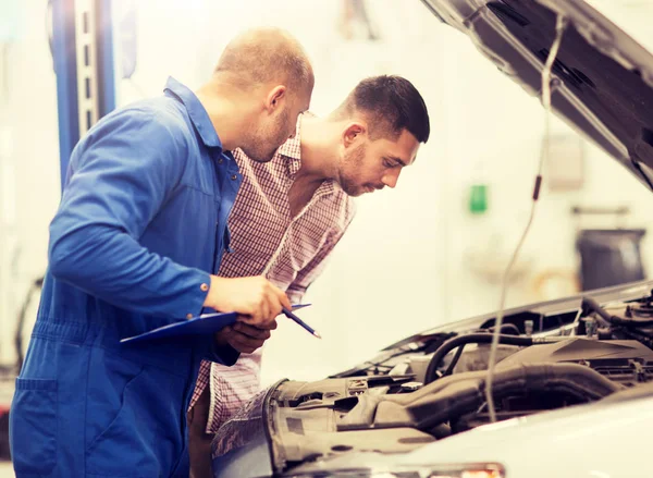 Automechaniker mit Klemmbrett und Mann im Autohaus — Stockfoto