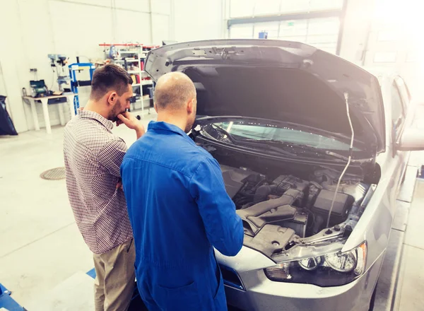 Auto szerelő és ember vagy autó tulajdonosa workshop — Stock Fotó