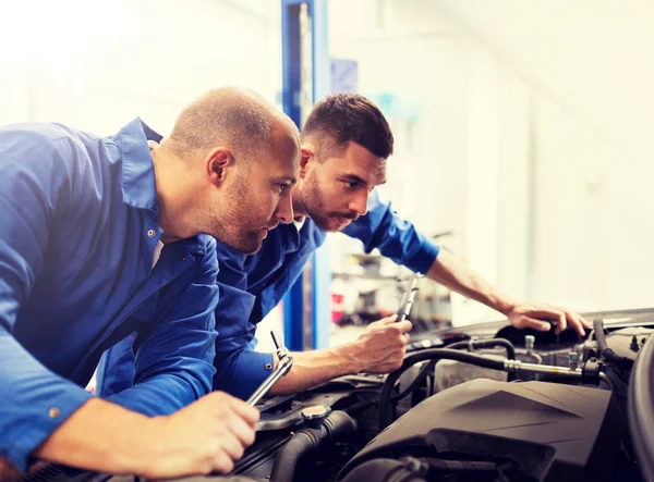 Hombres mecánicos con llave inglesa reparación de coches en el taller —  Fotos de Stock