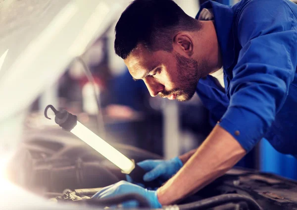 Mecánico hombre con lámpara de reparación de coches en el taller — Foto de Stock