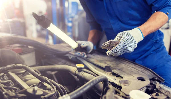 Monteur man met tangen repareren auto bij workshop — Stockfoto