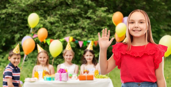 Uśmiechnięta dziewczyna macha ręką na przyjęcie urodzinowe w parku — Zdjęcie stockowe
