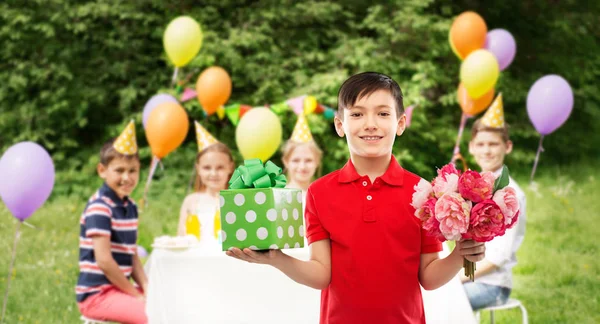 Niño con caja de regalo y flores en la fiesta de cumpleaños —  Fotos de Stock