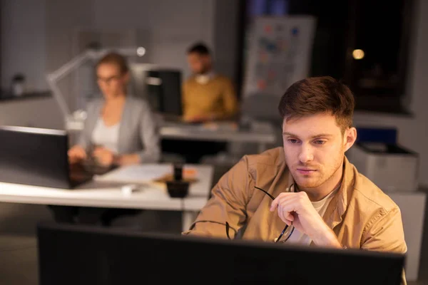 Человек с компьютером работает допоздна в ночном офисе — стоковое фото