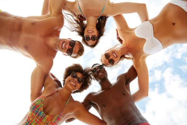 Счастливые друзья обнимаются над небом на летнем пляже — стоковое фото