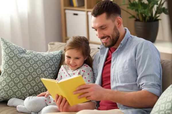 Happy father and daughter reading book at home Stock Picture